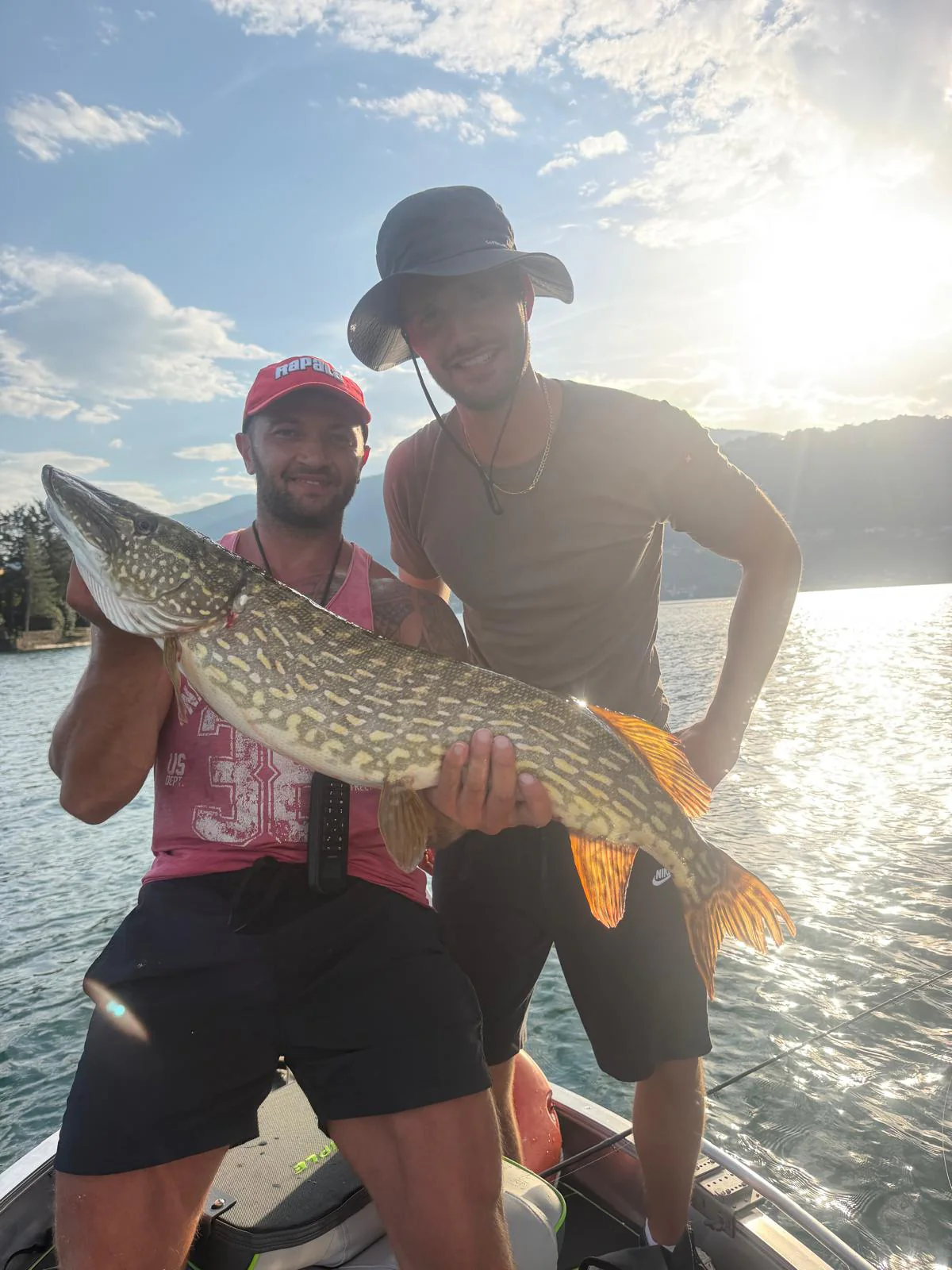 Manuel Bonetti con un luccio e un ospite a bordo, sul Lago d'Orta.